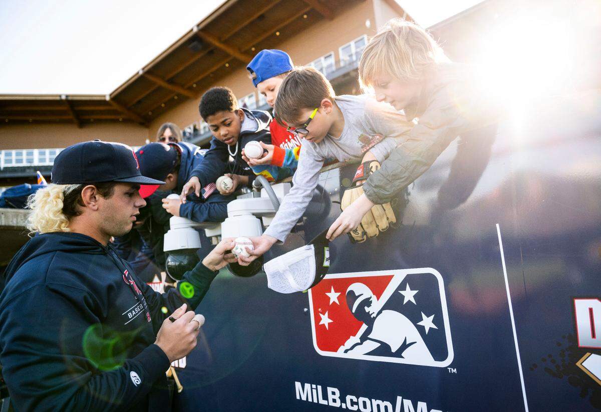 Tacoma Rainiers pitcher Taylor Dollard (41) signs a baseball for a young fan before the start of the Rainiers home opener game against the Reno Aces at Cheney Stadium in Tacoma, Wash. on April 4, 2023. The Rainiers won 12-5.