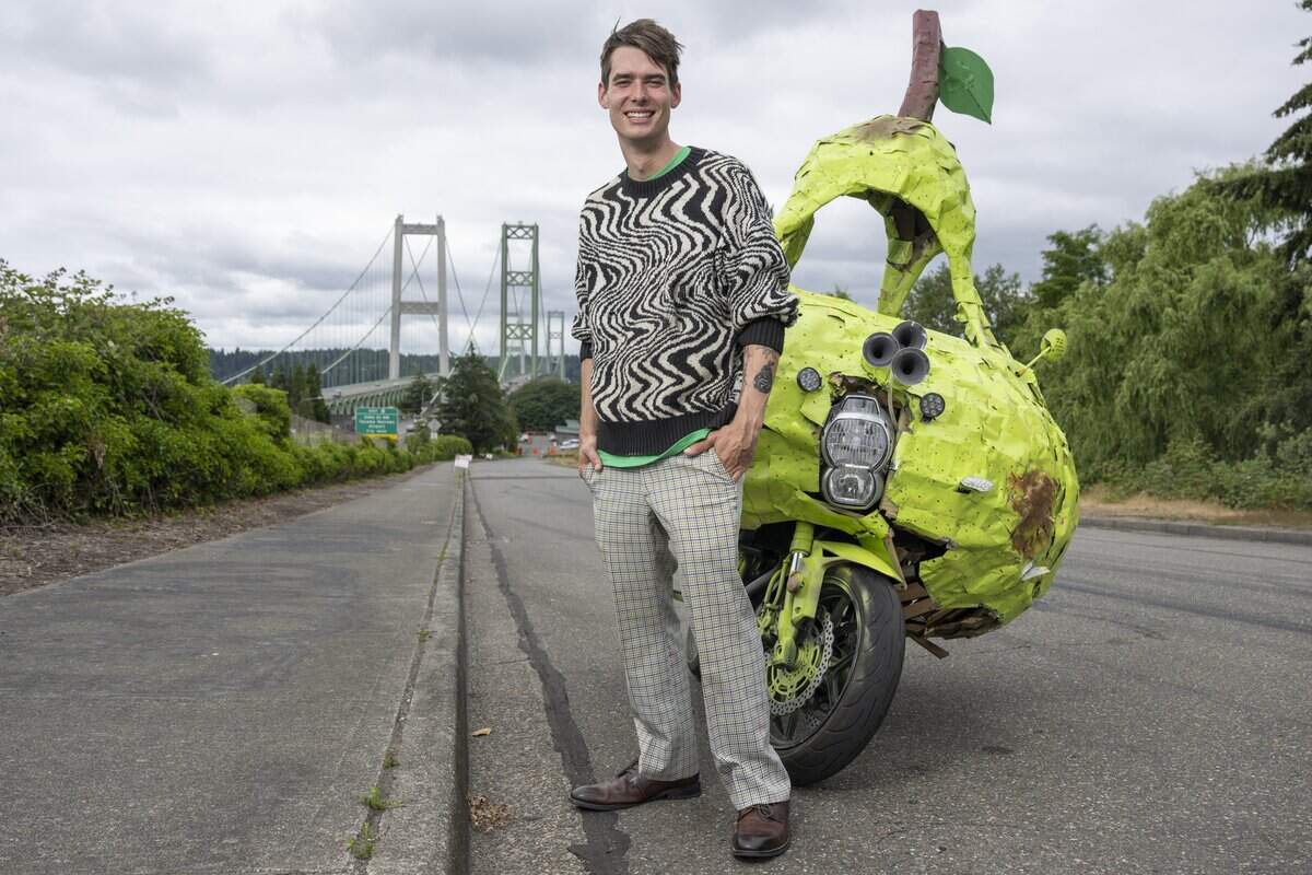 Andrew Glubbey stands by his Pear Car in view of the Tacoma Narrows Bridge on Wednesday, July 8, 2026, in Tacoma, Wash. Glubbey traveled from Florida to Washington on the motorcycle.