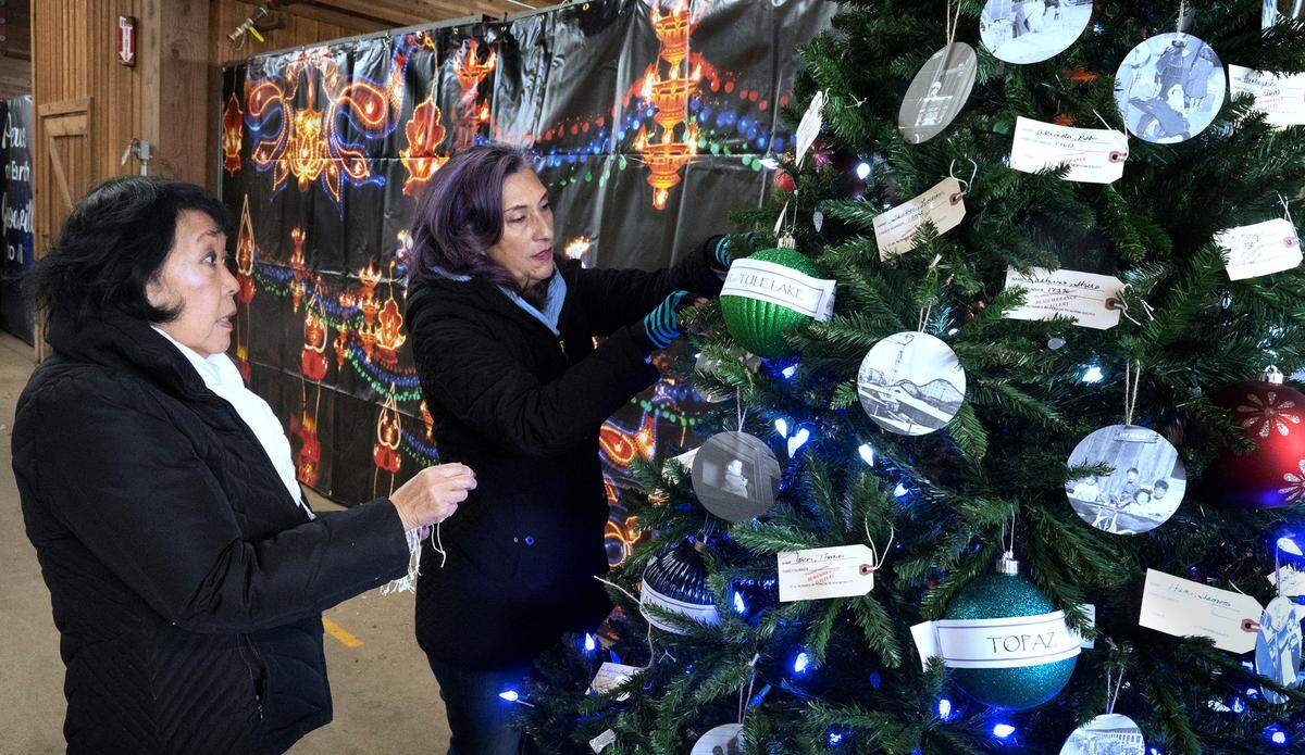 Eileen Yamada Lamphere (left) and project manager Sharon Sobie Seymour decorate the Japanese American Citizens League’s Christmas tree remembering the Northwest’s incarceration camps, including Camp Harmony at the Puyallup Assembly Center (now known as the Washington State Fairgrounds) in Puyallup, Washington. They are shown on Tuesday, Nov. 29, 2022.