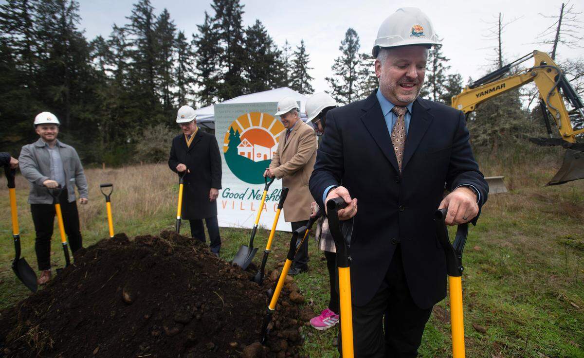 Duke Paulson, executive director of the Tacoma Rescue Mission, and others gather for groundbreaking ceremonies at the site of the new Good Neighbor Village in Spanaway on Thursday, Nov. 21, 2024. A few dozen protesters picketed outside the property, and at one point two women with signs walked onto the property confronted by security.