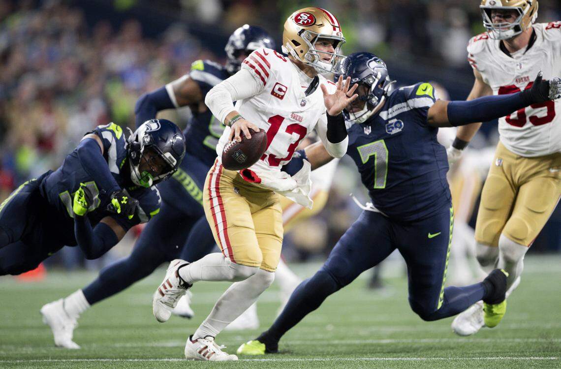 San Francisco 49ers quarterback Brock Purdy (13) scrambles under pressure from the Seattle Seahawks defense during the third quarter of the NFC Divisional Round game at Lumen Field, on Saturday, Jan. 17, 2026, in Seattle.