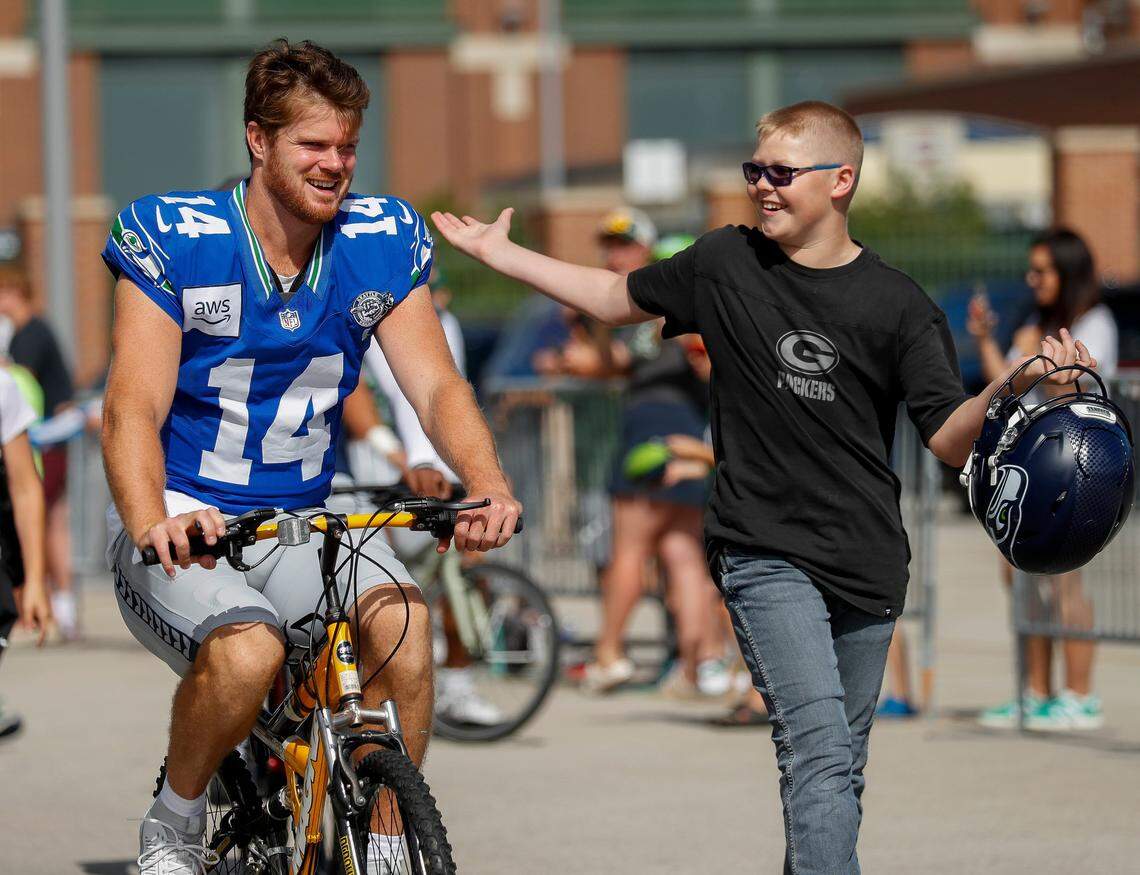 Seattle Seahawks quarterback Sam Darnold (14) shares a laugh with a fan as he rides a bicycle to a joint practice with the Green Bay Packers on Thursday, August 21, 2025, at Lambeau Field in Green Bay, Wis. Tork Mason/USA TODAY NETWORK-Wisconsin