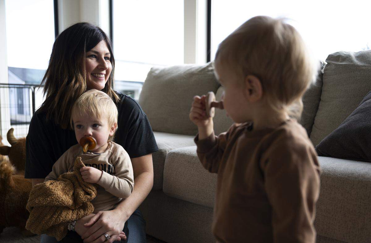 Kailee Pederson holds her son Crew while twin Lake plays at home, on Friday, Jan. 9, 2026 in Buckley, Wash. The twins were born after severe complications during pregnancy in May 2024. Lake recently underwent surgery for his lungs. 