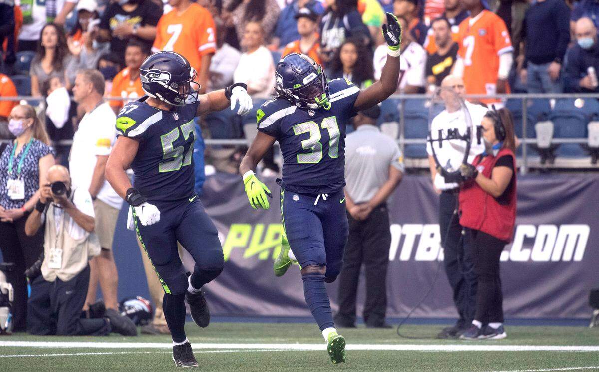 Seahawks running back DeeJay Dallas (31) celebrates with teammate Cody Barton following a long kick-off returns against the Denver Broncos during Saturday night’s NFL preseason football game at Lumen Field in Seattle, Washington, on Saturday, Aug. 21, 2021.