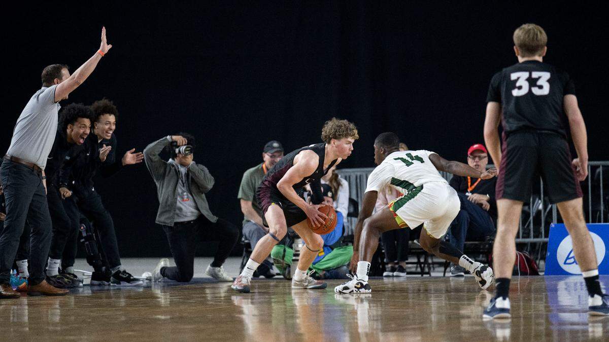 Auburn guard Luvens Valcin (14) guards Mount Spokane guard Ryan Lafferty (3) as the Auburn bench cheers Valcin on during the second quarter of the Class 3A 3rd/5th-place game on Saturday, March 4, 2023, in Tacoma, Wash.