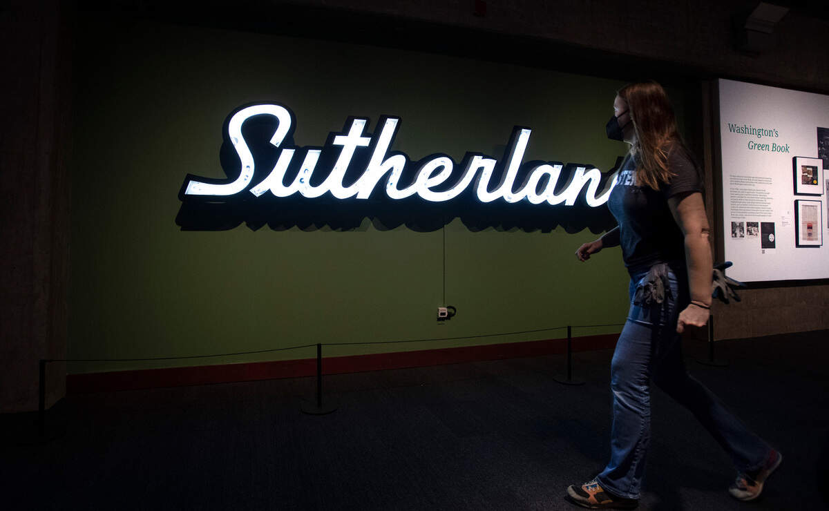 Exhibit installer Sarah Crouse walks through “The Green Book” exhibit at the Washington State Historical Museum in Tacoma, Washington, on Thursday, March 17, 2022. The Green Book travel guide was created by Victor Green to provide African Americans with critical information on restaurants, gas stations, department stores, accommodations and other businesses that welcomed Black travelers during the era of Jim Crow and “sundown towns.