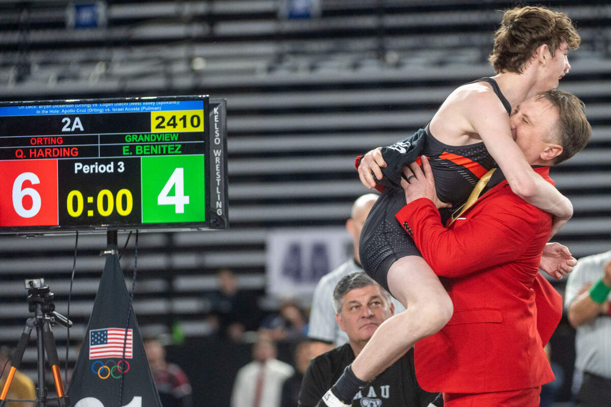 Orting’s Quentin Harding jumps into the arms of head coach Jody Coleman after beating Grandview’s Evan Benitez in their 126-pound, Class 2A championship match at Mat Classic XXXIV on Saturday, Feb. 18, 2023, at the Tacoma Dome in Tacoma, Wash.