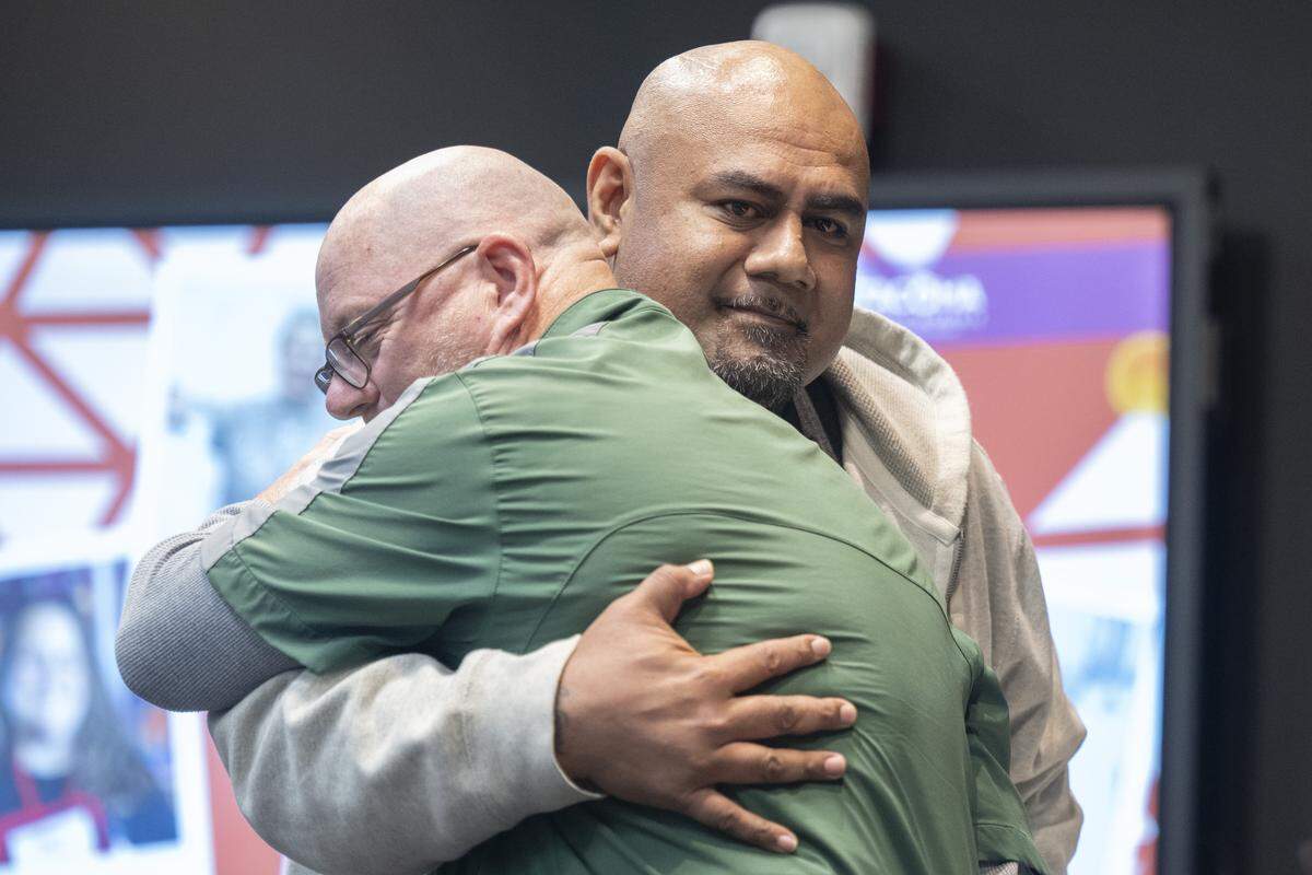 Foss High School coach David (Coach Mac) McEachern, left, and High School campus security guard Bonhoeffer (Bon) Muao embrace on Thursday, May 14, 2026, as they are called on stage to be recognized for intervening during an aggravated assault at Foss in April. McEachern and Muao received the Medal of Courage, alongside other staff members.