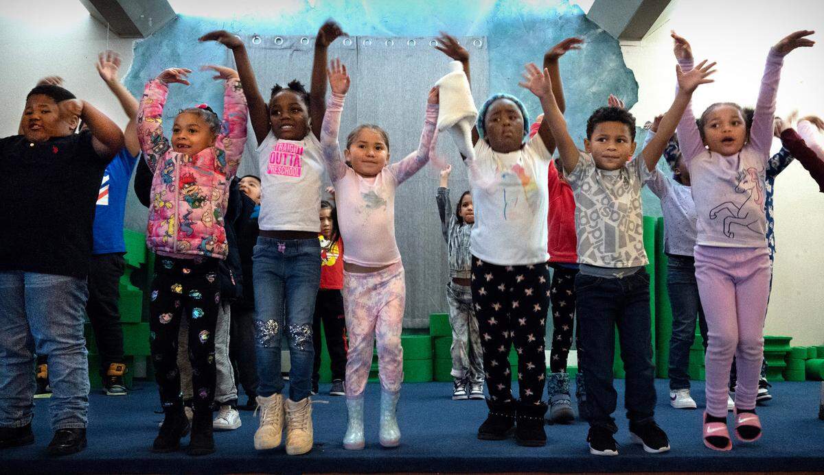 School kids sing and dance around the stage during the Music and Movement morning activities at the Multicultural Child and Family Hope Center’s Community Hall in the Hilltop neighborhood of Tacoma, Washington, on Wednesday, Nov. 1, 2023. The center is on a multi-million dollar capital campaign to expand their location and services.