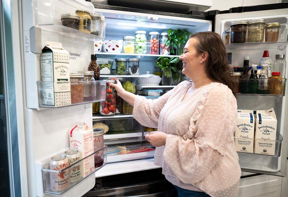 Amy Cross, founder of The Cross Legacy, places strawberries that have been prepared to be preserved for over three weeks in her refrigerator at her home in Bonney Lake, Wash. on Dec. 7, 2022. Amy has amassed over 140,000 followers over the course of a year from sharing tips on social media platforms and her blog about how to preserve food and fresh produce to save money on groceries.