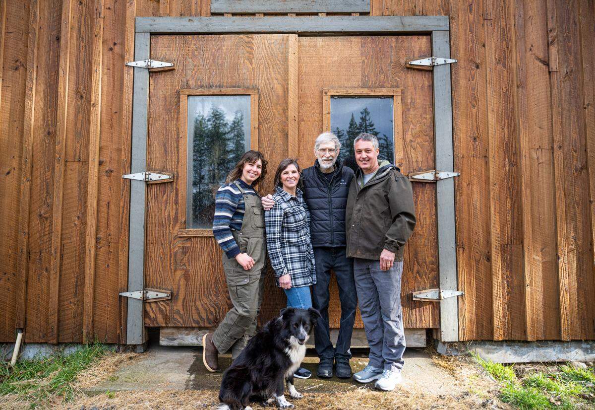 Petra Cole, left, her mother, Sarah Cole, her grandfather, Tom Karlin, and her father, Brad Cole, right, pose for a portrait in front of a barn on their property in Eatonville. on Jan. 5, 2023. Over 60 years ago, Petra’s great-grandparents purchased 40 acres of land where five families including the Cole’s and other relatives now live adjacent to each other on 25 acres of the property.