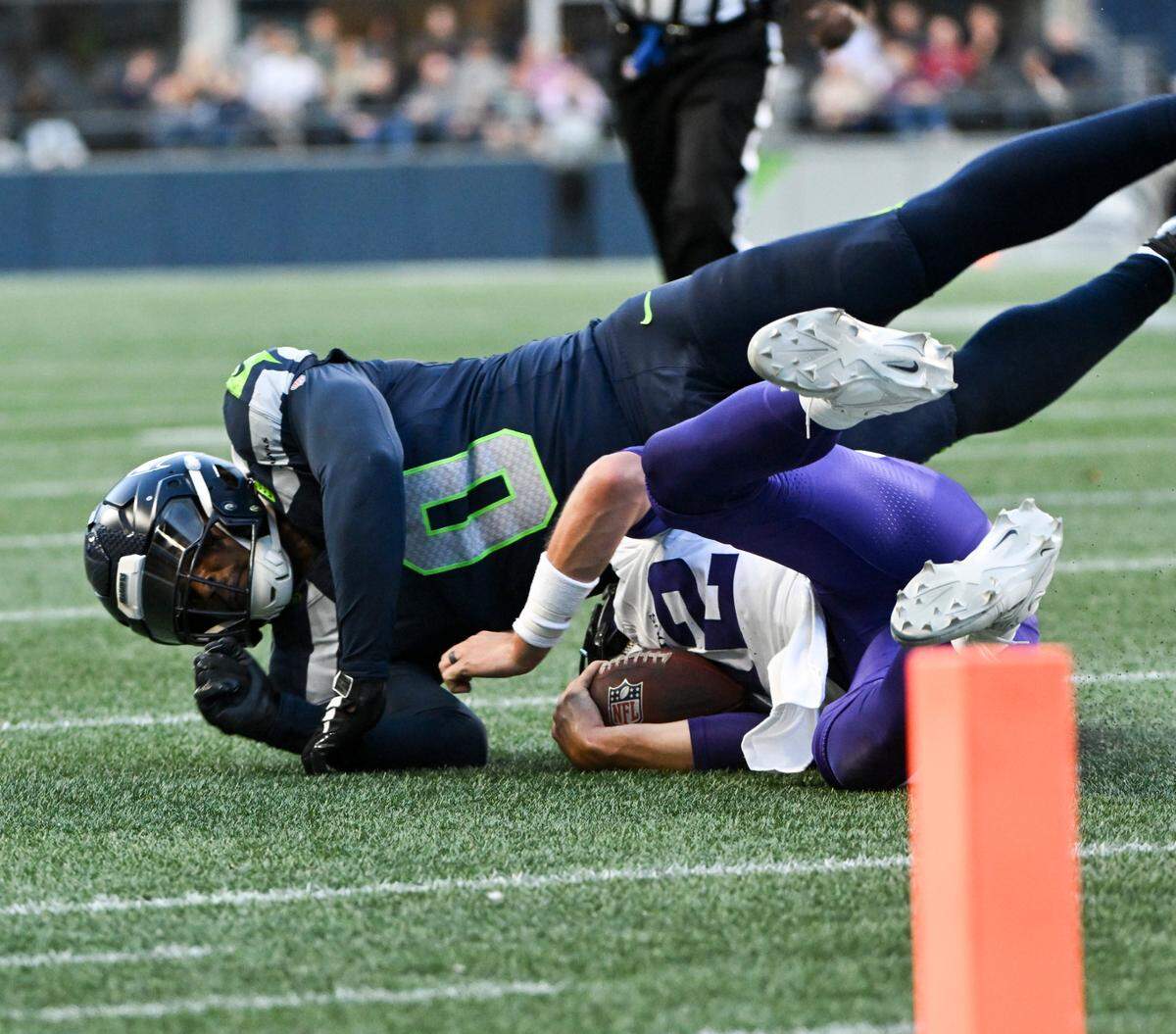Seattle Seahawks linebacker Devin Bush (0) brings down Minnesota Vikings quarterback Nick Mullens (12) during the first quarter of the preseason game at Lumen Field, Thursday, Aug. 10, 2023, in Seattle, Wash.