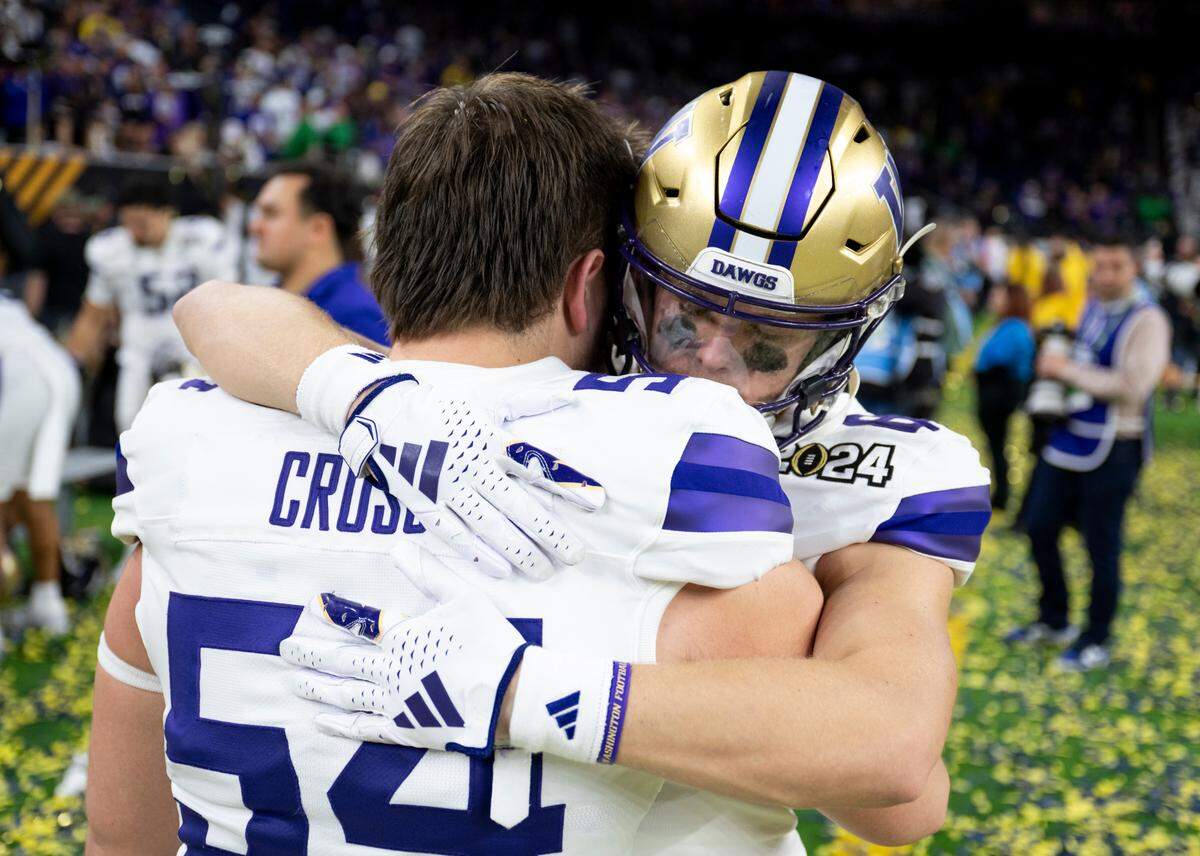 Washington Huskies offensive lineman Parker Cross (54) and Washington Huskies wide receiver Jackson Girouard (84) hug after the Washington Huskies 34-13 lose to Michigan Wolverines in the College Football Playoff National Championship game at NRG Stadium on Monday, Jan. 8, 2024, in Houston.