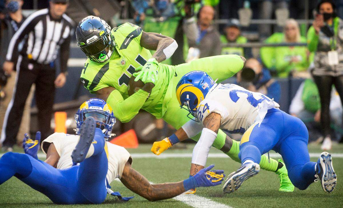 Seattle wide receiver DK Metcalf bowls over Los Angeles defensive backs Jordan Fuller (left) and Taylor Rapp for a touchdown reception to open scoring in the NFL’s Thursday Night Football game at Lumen Field in Seattle, Washington, on Oct. 7, 2021.