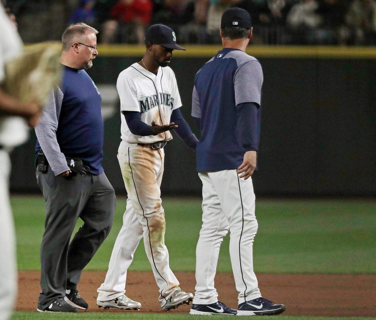 Seattle Mariners second baseman Dee Gordon, center, walks off the field with a trainer, left, and manager Scott Servais, right, after Gordon suffered an injury in the ninth inning of a baseball game against the Toronto Blue Jays, Thursday, Aug. 2, 2018, in Seattle. The Blue Jays won 7-3. (AP Photo/Ted S. Warren)