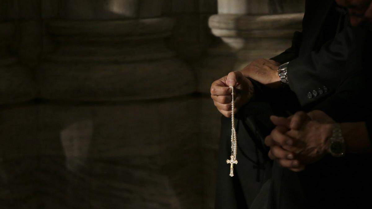 A member of the clergy prays the rosary as he waits for Pope Francis to arrive at St. Patrick’s Cathedral for evening prayer service in New York in 2015. The Catholic church’s ongoing sex abuse scandal recently took a new turn in Tacoma with a release of names of potential offenders who were assigned to Bellarmine Preparatory School.