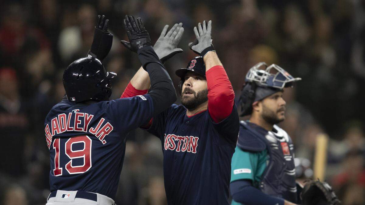 Boston Red Sox’s Mitch Moreland, center, is congratulated by Jackie Bradley Jr., after hitting a three-run home run off of Seattle Mariners Hunter Strickland during the ninth inning of a baseball game Friday, March 29, 2019, in Seattle. (AP Photo/Stephen Brashear)