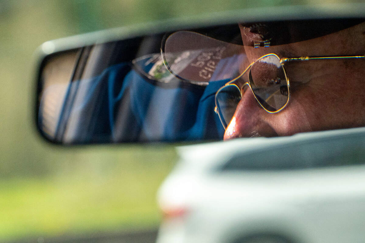 Larry Geringer, a C.O.P.S volunteer with the Gig Harbor Police Department, is seen in the rearview mirror the the department’s volunteer patrol car as he cruises around the harbor on Wednesday, April 6, 2022, in Gig Harbor, Wash.