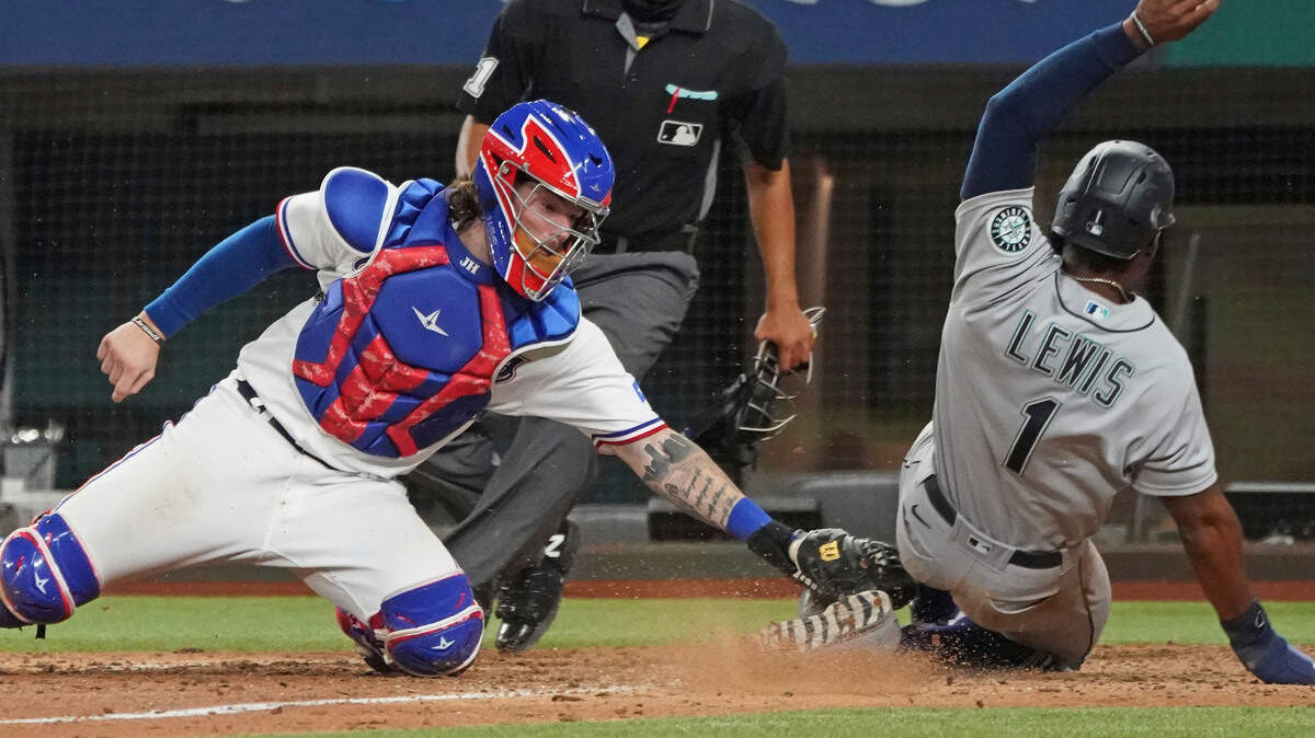 Seattle Mariners base runner Kyle Lewis is tagged out at home by Texas Rangers catcher Jonah Heim to end a baseball game in the ninth inning Saturday, May 8, 2021, in Arlington, Texas. (AP Photo/Louis DeLuca)