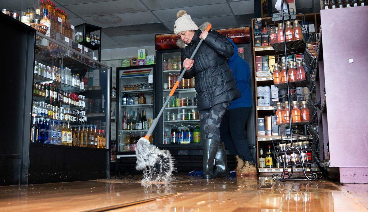 Store owner Laura Scheel mops floodwater from her Purdy Liquor Market that was filled with knee-deep water in Purdy, Washington, on Tuesday, Dec. 27, 2022.