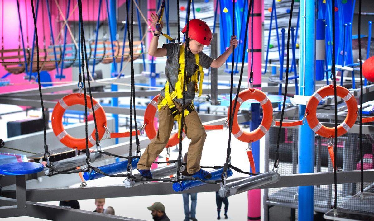 Brodi Brundage, 7, of Puyallup works his way across the Flying Leopard ropes course ten feet abve the ground at Catapult Adventure Park in Puyallup, Washington, on Friday, Dec. 24, 2021.