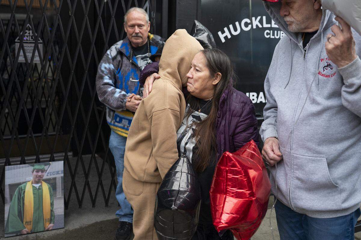 Tina Ramirez-Oya hugs grandmother Kimberly Nystrom, center right, as they stand along Martin Luther King Jr. Way in the Hilltop neighborhood, where Steven Speakman, Nystrom’s son, was fatally shot 10 years earlier. Photographed on Monday, Nov. 3, 2025, in Tacoma. Family of Speakman gathered for a balloon release in his honor.