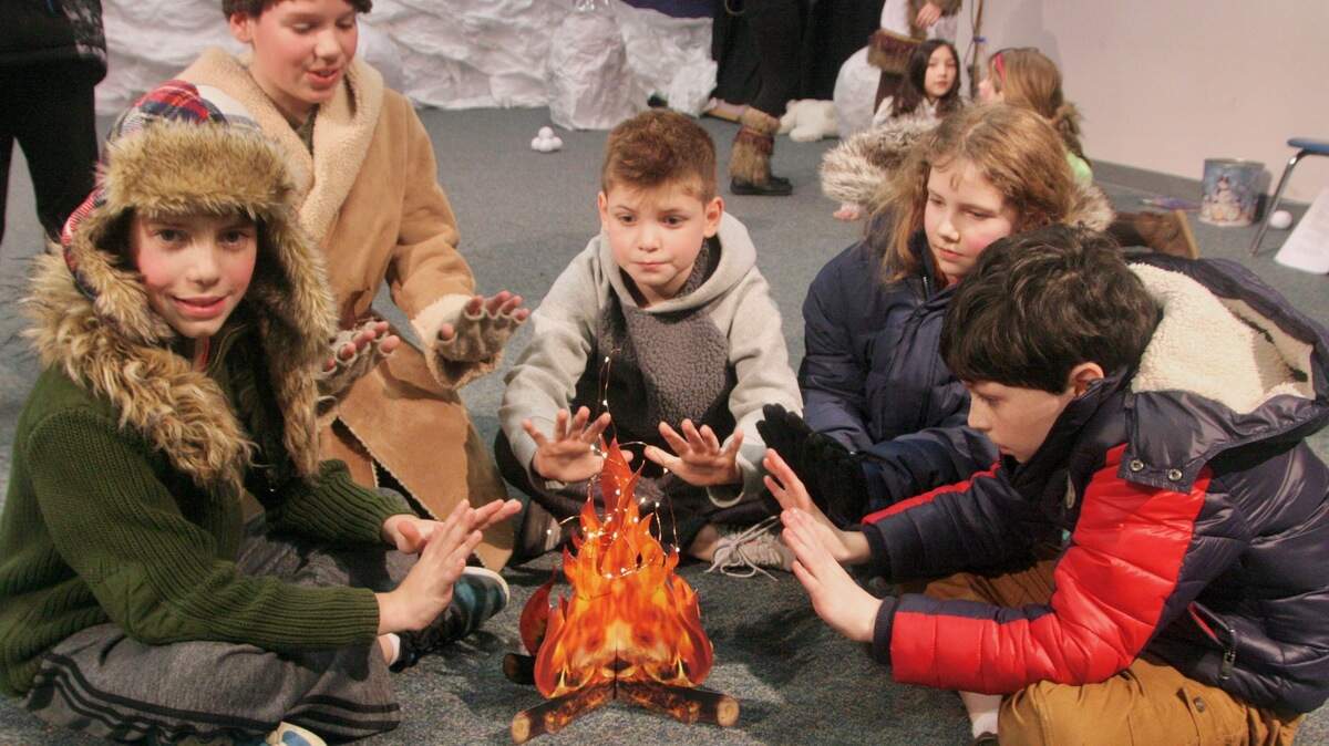 Dressed for the frozen north, fourth-graders at Harbor Heights elementary huddle around a “campfire” during their play about polar winter.