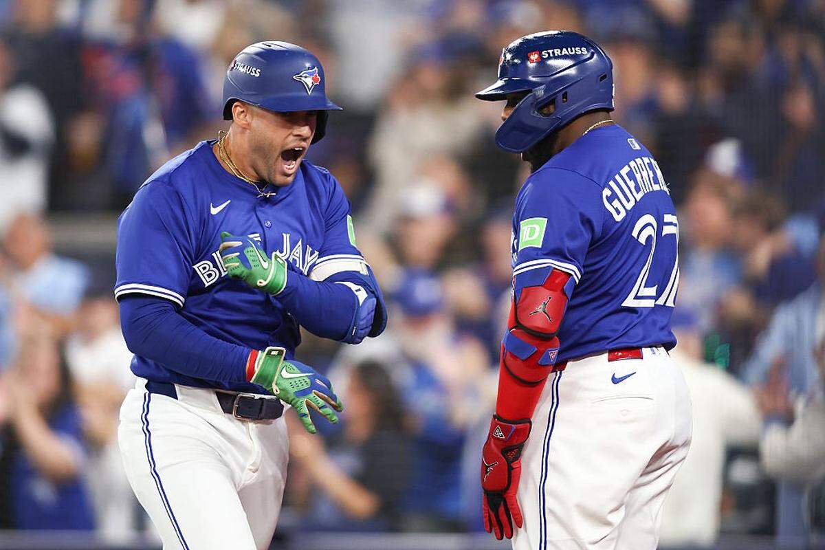 TORONTO, ONTARIO - OCTOBER 12: George Springer #4 of the Toronto Blue Jays is congratulated by Vladimir Guerrero Jr. #27 after hitting a solo home run against the Seattle Mariners during the first inning in game one of the American League Championship Series at Rogers Centre on October 12, 2025 in Toronto, Ontario. (Photo by Cole Burston/Getty Images)