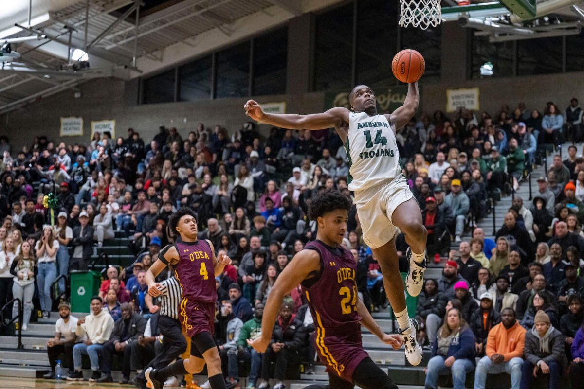Auburn guard Luvens Valcin (14) dunks the ball on a fast break as O’Dea guard B.J. Shannon (24) gets out of the way during the second quarter of a Class 3A state regionals game on Saturday, Feb. 25, 2023, at Auburn High School in Auburn, Wash.