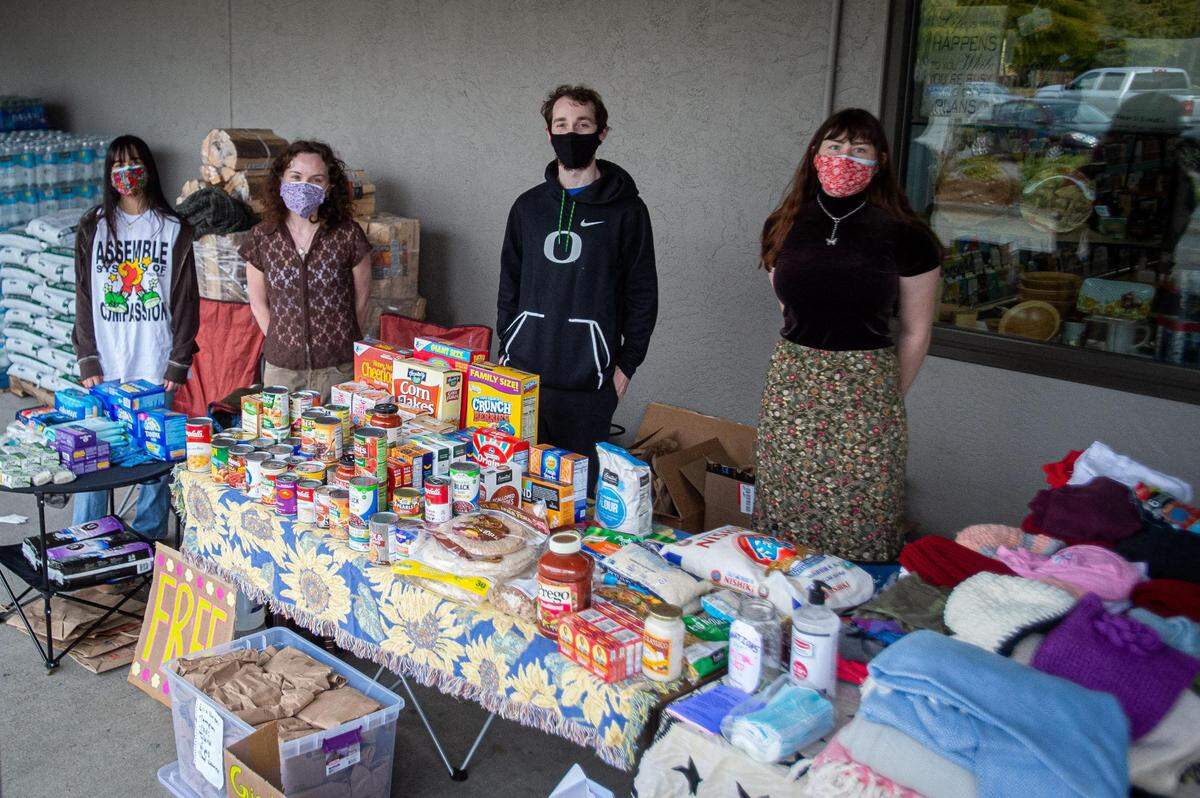 From left: Reagan Trim, Hannah Lerman, Joe McAlister, and Violet Cronemeyer stand for a portrait at the Gig harbor Mutual Aid resources booth they set up outside Lake Kathryn Market in Wauna, Wash., on Saturday, April 3, 2021. The booth offers free food items, clothing, and personal hygiene items to those in need in the area.