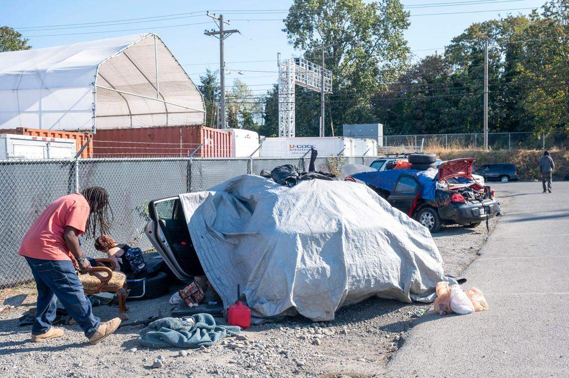 Wolf (left), who asked not to use his last name, cleans up around his car where he is living out of along M Street near the 1200 block of Puyallup Avenue in Tacoma on Sept. 20, 2022. This week the Tacoma City Council passed an ordinance that prohibits camping in a 10-block radius around public property where temporary shelters are located.