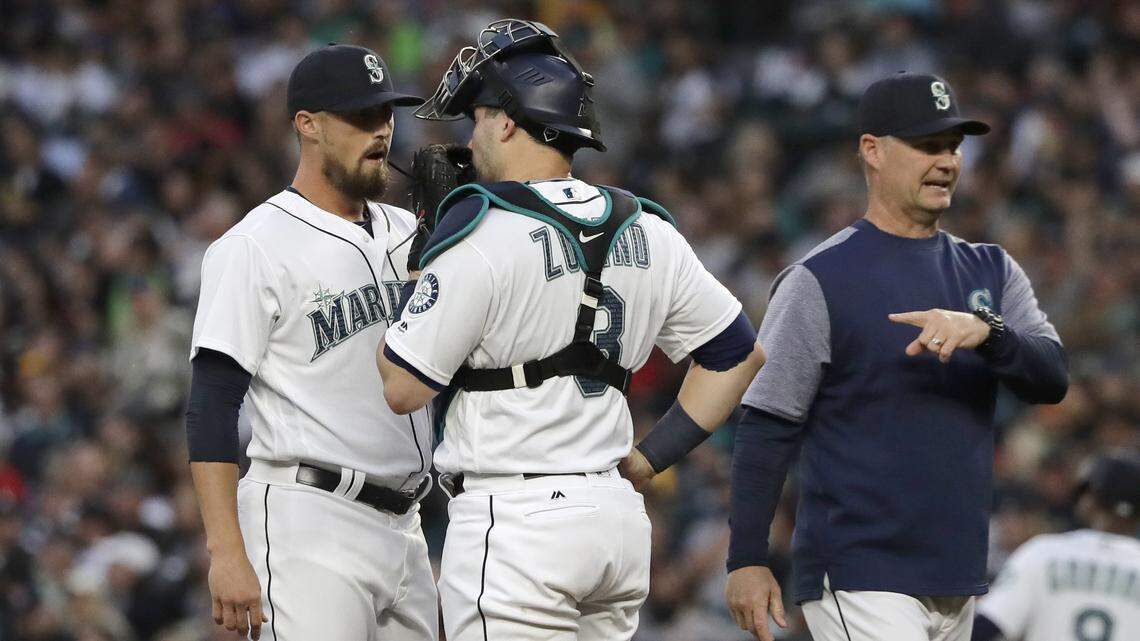 Seattle Mariners manager Scott Servais, right, points towards the mound as relief pitcher Shawn Armstrong, left, talks to catcher Mike Zunino after Armstrong replaced starter Felix Hernandez during the fifth inning of a baseball game against the New York Yankees, Saturday, Sept. 8, 2018, in Seattle. (AP Photo/Ted S. Warren)