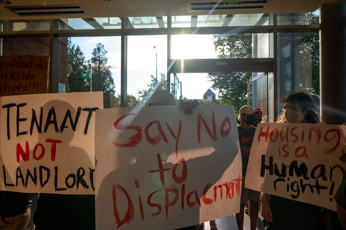 People hold up signs in support of fair housing as they enter Puyallup City Hall prior to the start of a Puyallup City Council meeting on Tuesday, Aug. 23, 2022, in Puyallup, Wash. Over 50 people gathered in Pioneer Park to rally in support of the residents of Meridian Mobile Estates and speak at the city council meeting on Tuesday evening.