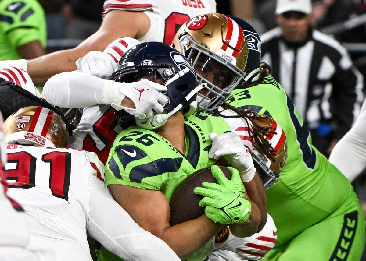San Francisco 49ers linebacker Fred Warner (54) gets a hand inside Seattle Seahawks running back Zach Charbonnet (26) facemark during the second quarter of the game at Lumen Field, Thursday, Nov. 23, 2023, in Seattle, Wash.