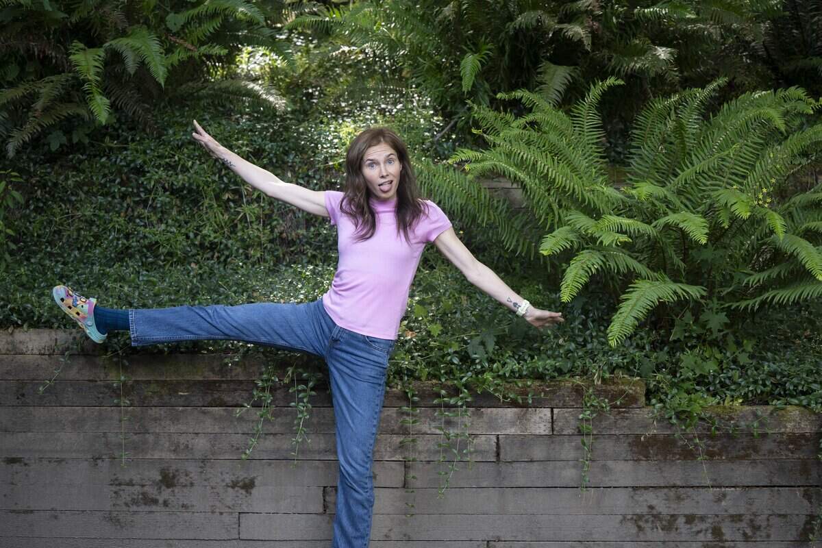 Amanda Knox throws her arms and leg in the air for a portrait outside of her home on Tuesday, July 7, 2026, in Vashon, Wash. Knox will star in a one-woman show, “Cartwheel,” at the Tacoma Little Theatre in July.