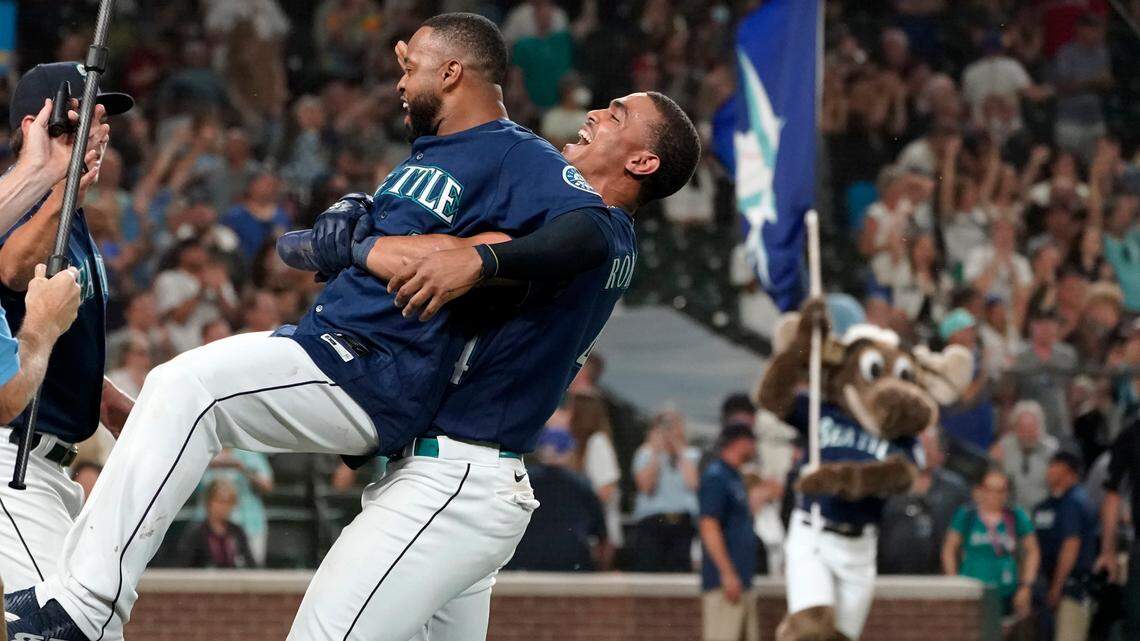 Seattle Mariners’ Carlos Santana, left, is lifted up by Julio Rodriguez, right, after Santana hit a walk-off sacrifice fly in the ninth inning of a baseball game against the Texas Rangers to score Cal Raleigh, Tuesday, July 26, 2022, in Seattle. The Mariners won 5-4. (AP Photo/Ted S. Warren)