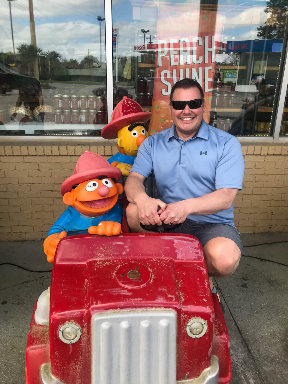 Jeff Conover riding a fire engine with Sesame Street characters Bert and Ernie in March 2021.