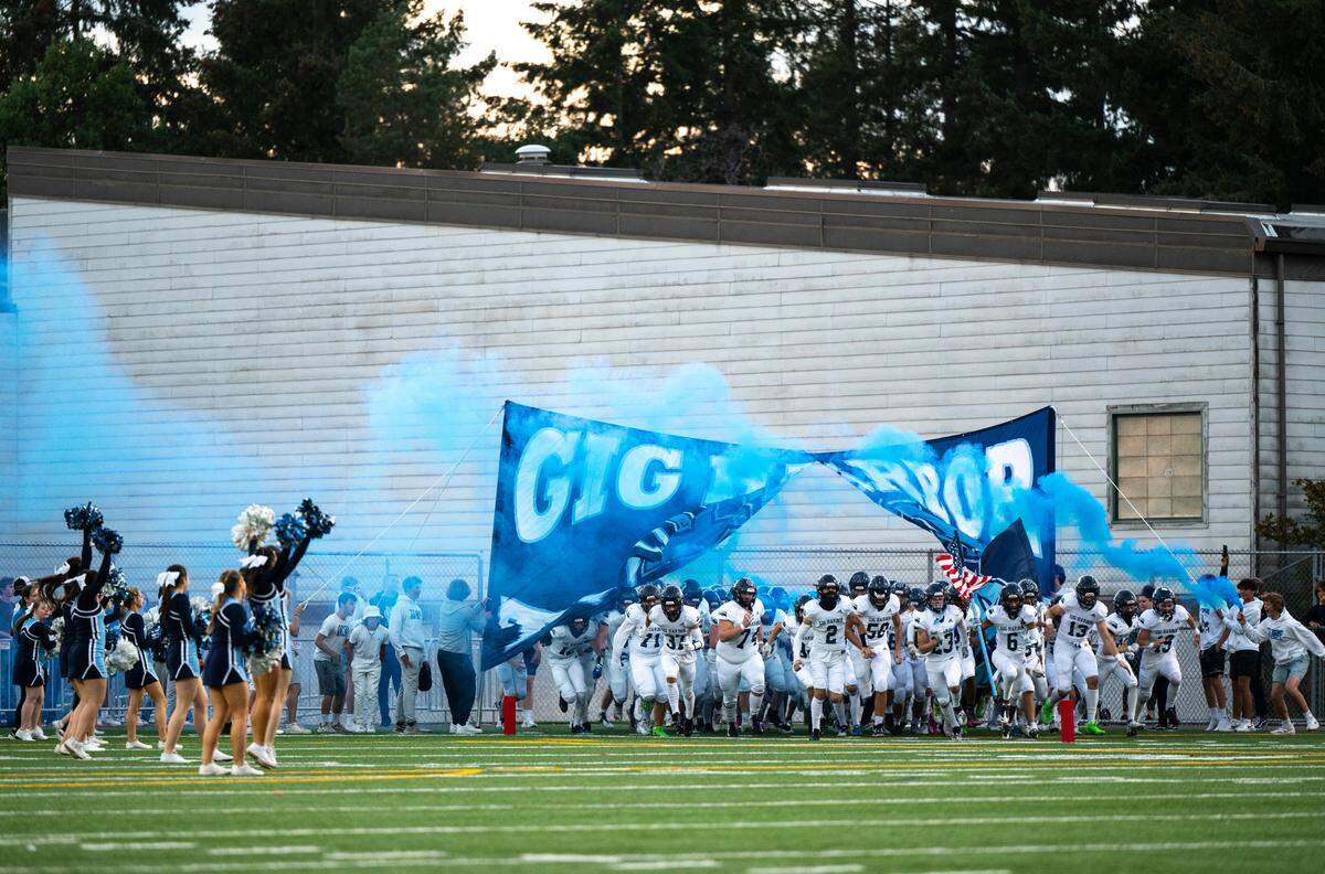 Gig Harbor’s varsity football team runs through a banner and onto the field before the start of a game against Timberline at the Roy Anderson Field in Purdy, Wash. on Sept. 29, 2022. Gig Harbor lost to Timberline 34-36 in overtime.