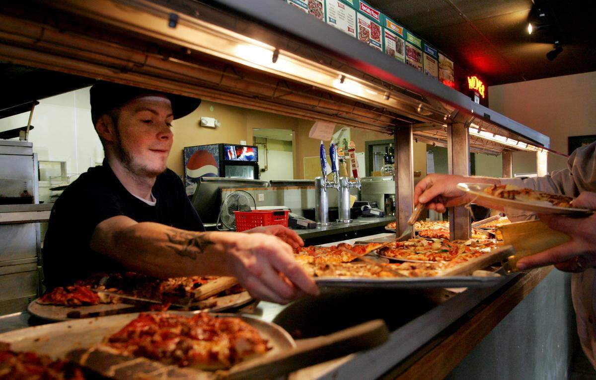 Cory Cline dishes up pizza for the lunch buffet at Round Table Pizza in Tacoma, February 11, 2009. The Monday through Friday all-you-can eat deal for $5.93 is popular.(Janet Jensen/The News Tribune)