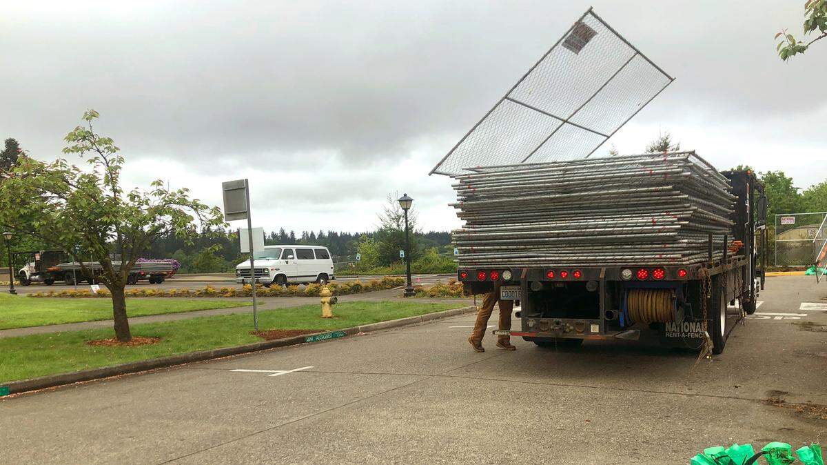 Workers remove fencing around key buildings on Washington state’s Capitol Campus in Olympia on Tuesday morning. The security fences had been there since January.