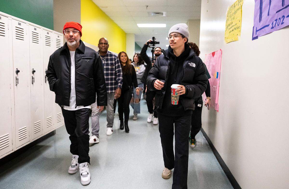 Comedian Jo Koy, left, walks down the hallways of his alma mater Foss High School, with his son, Joe Herbert Jr., in Tacoma on Nov. 29, 2022.
