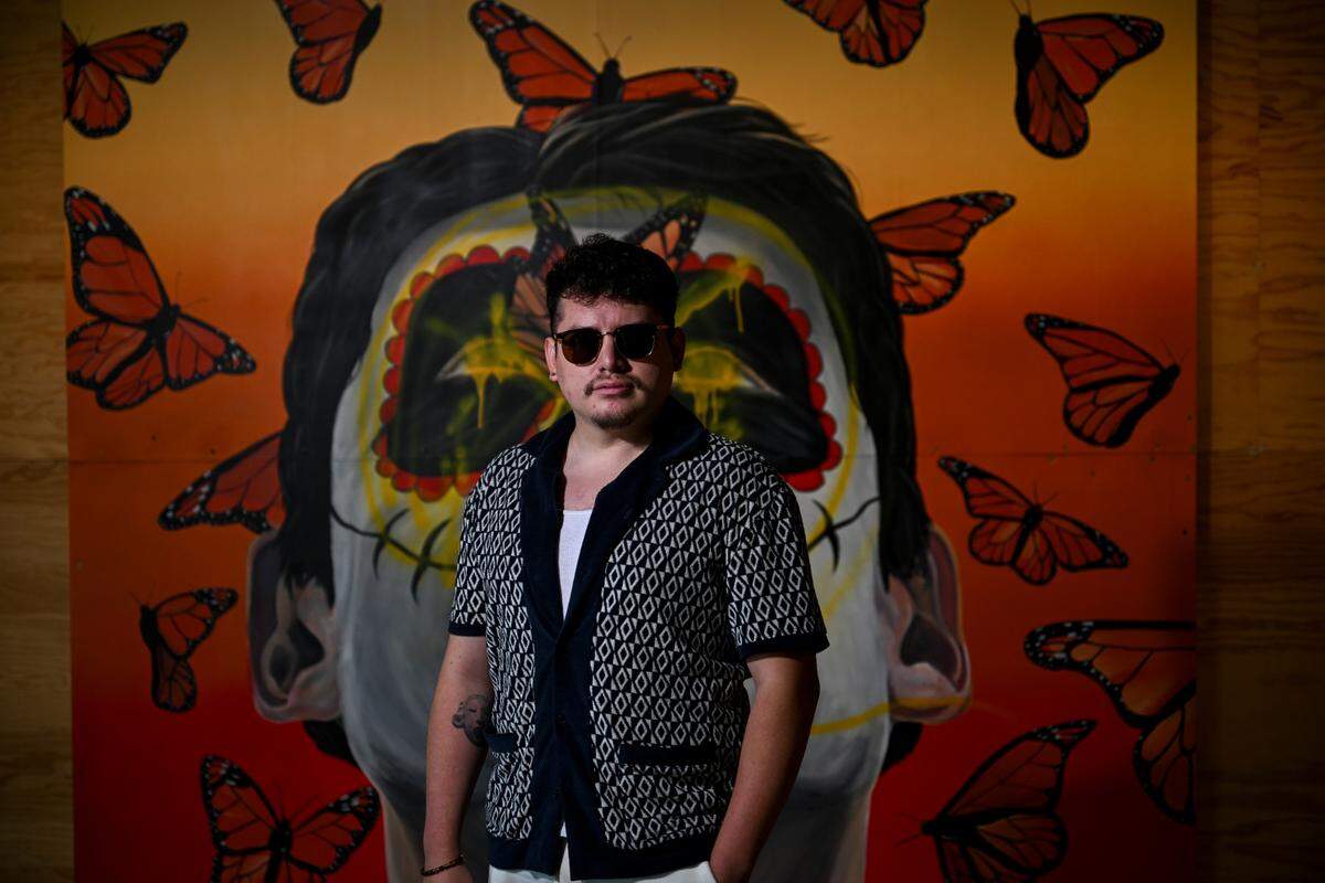 Gerardo Peña poses with his mural titled “The Monarch Butterfly” at ALMA Cafe, Friday, Aug. 18, 2023, in Tacoma, Wash.