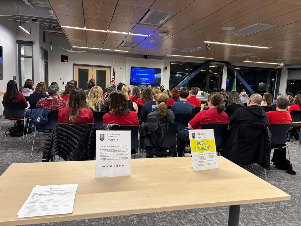 Citizens gather at the Puyallup School District board meeting at the Kessler Center on March 2, 2026. Many wore red, the color of the Puyallup Education Association, and spoke out in public comment to protest the district’s incoming $15 million budget cuts.