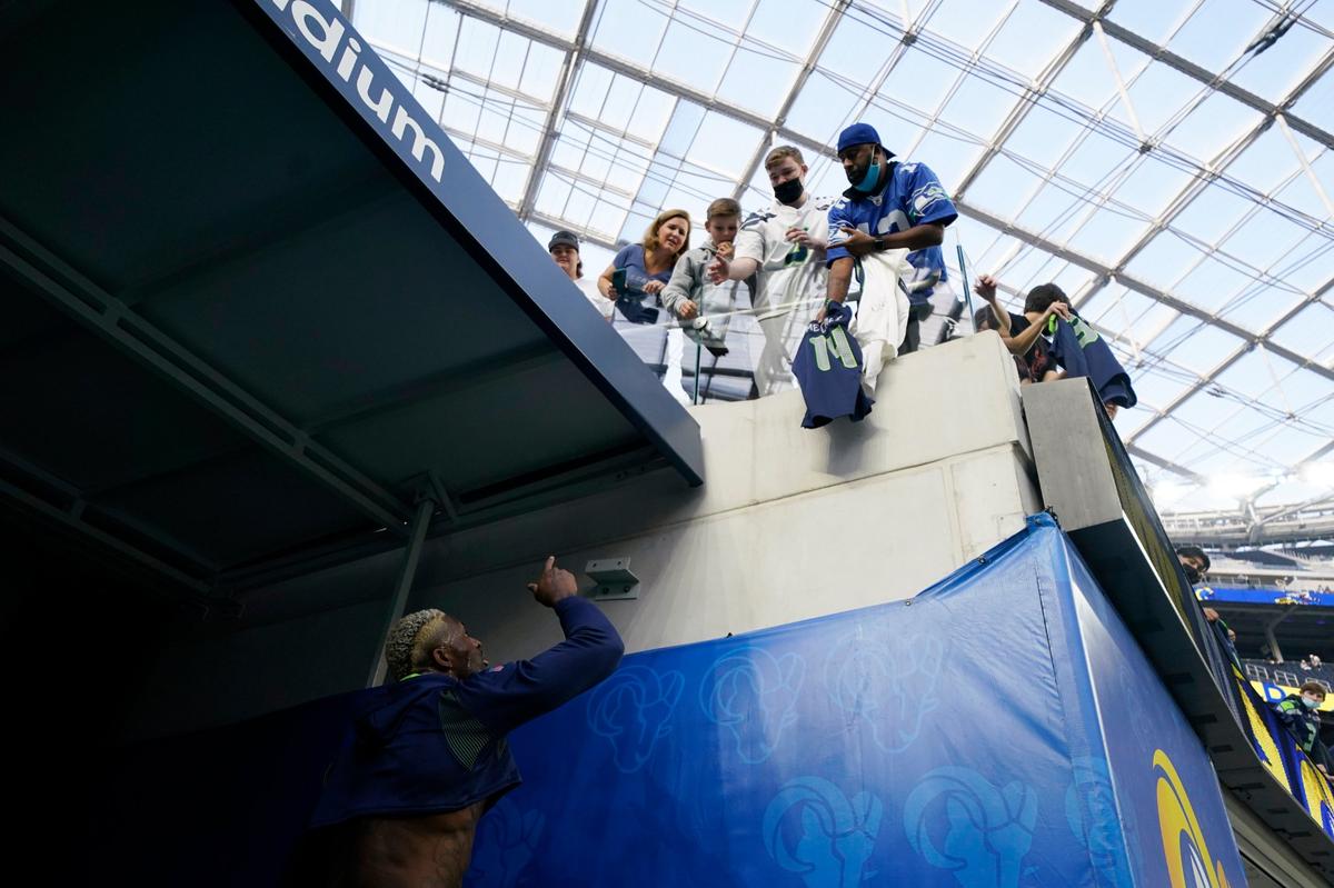 Seattle Seahawks wide receiver DK Metcalf, bottom, talks with fans before an NFL football game against the Los Angeles Rams Tuesday, Dec. 21, 2021, in Inglewood, Calif. (AP Photo/Ashley Landis )