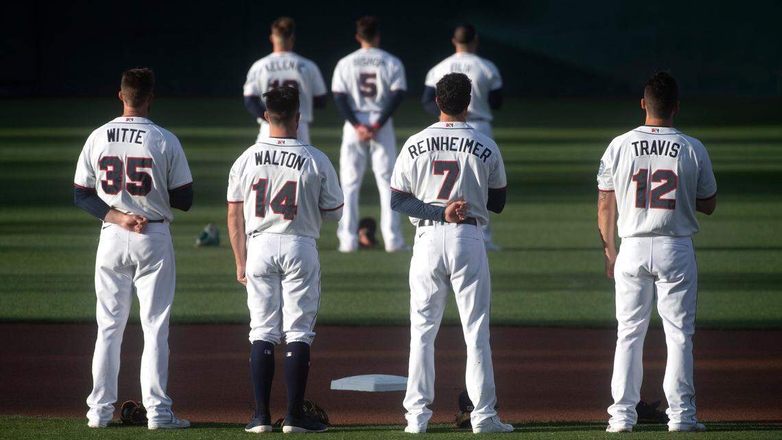 Tacoma Rainiers players stand at attention during the national anthem during opening ceremonies for Thursday night’s season opener against the El Paso Chihuahuas at Cheney Stadium in Tacoma, Washington, on Thursday, May 6, 2021.