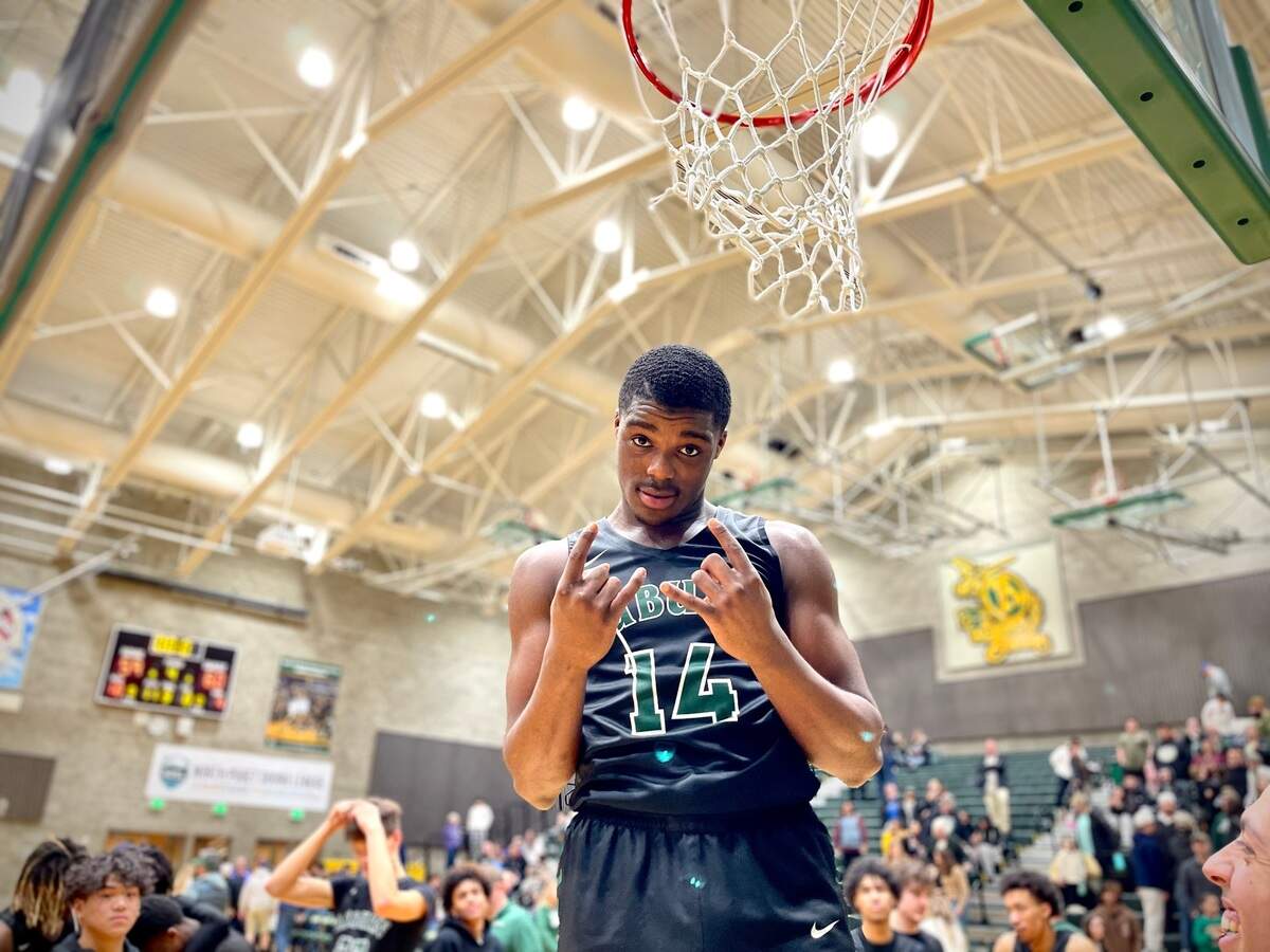 Auburn High School junior Luvens Valcin poses after cutting down a piece of the net after Auburn’s 3A District 3/4 championship game win over Gig Harbor on Saturday, Feb. 18, 2023 at Auburn High School.