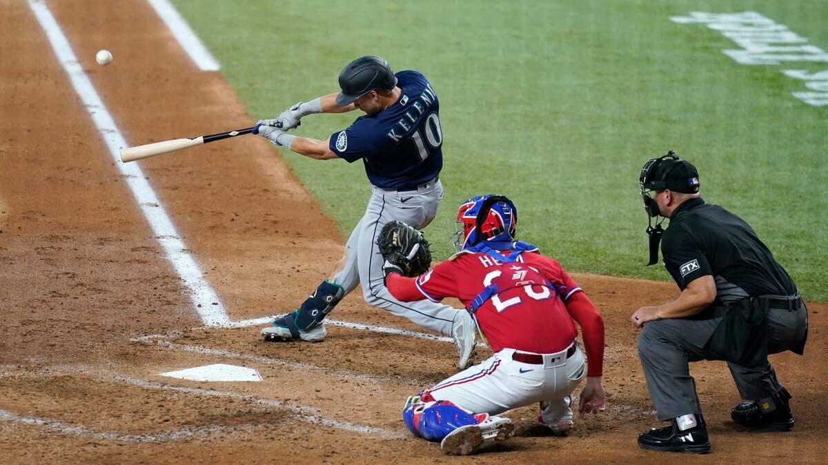 Seattle Mariners’ Jarred Kelenic (10) connects for a three-run home run in front ot Texas Rangers’ Jonah Heim and umpire Scott Barry during the third inning of a baseball game in Arlington, Texas, Friday, July 30, 2021. (AP Photo/Tony Gutierrez)