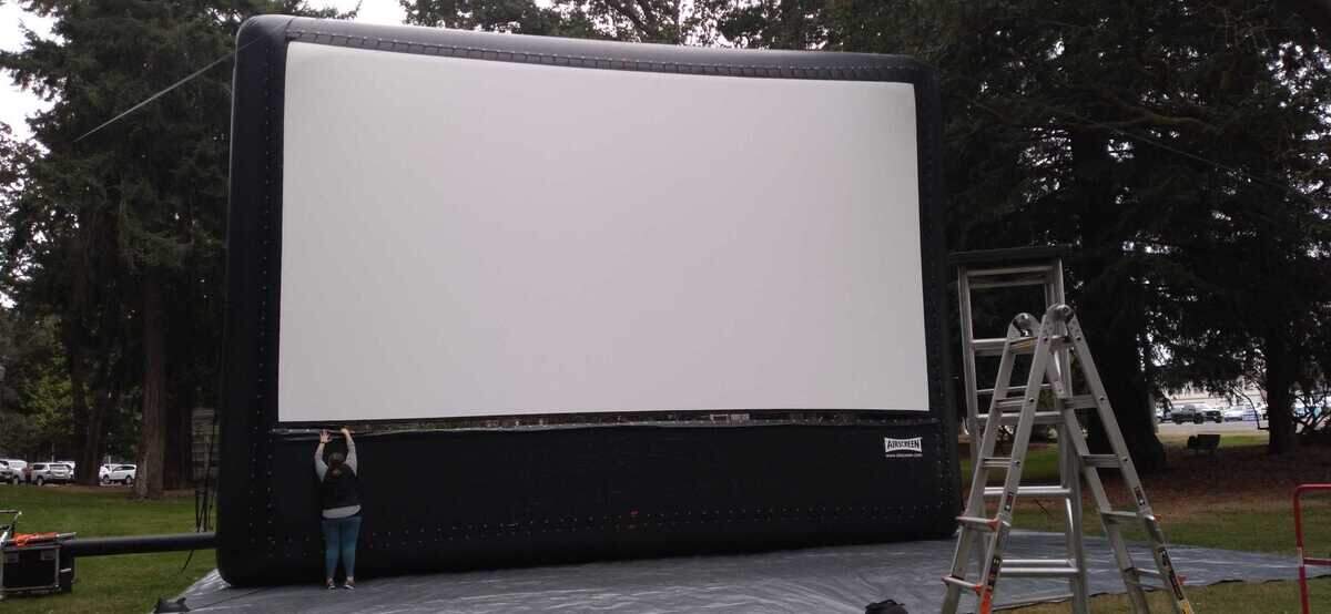 The Grand Cinema’s 30-foot-wide outdoor projector is set up at a park for one of last summer’s movie screenings.
