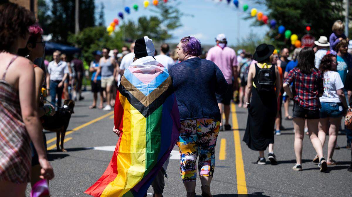 Cheyenne Wright, 14, left, walks down Pacific Avenue with her mother, Emily Wright, while wearing a progress pride flag during the Tacoma Pride Festival in Tacoma on July 9, 2022.