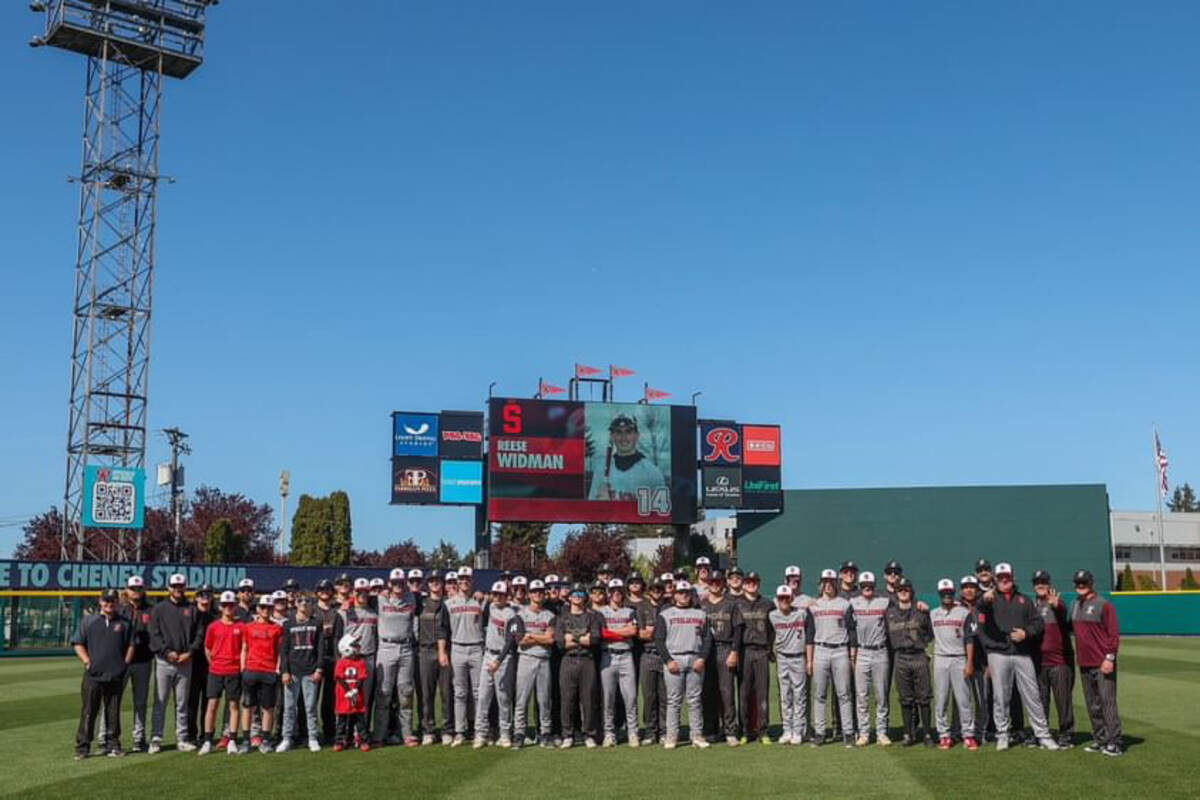 Steilacoom and Enumclaw high schools’ baseball teams pose for a picture in front of the scoreboard with former Steilacoom baseball player Reese Widman’s photo. Widman died in January 2023.